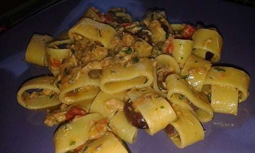 un buon piatto di pasta calamarata con tonno, olive e capperi